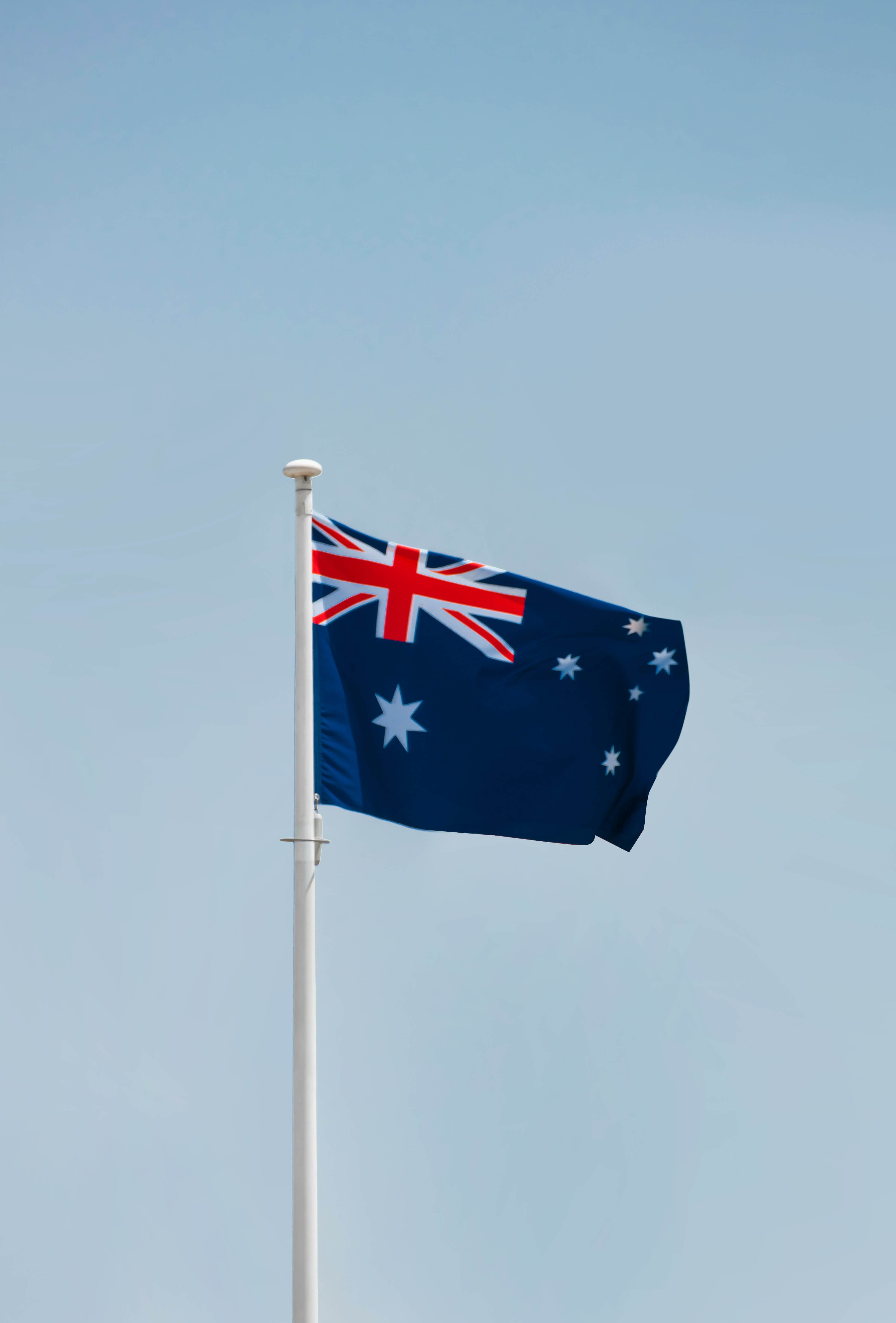 The Australian flag with a blue sky background. loading=lazy