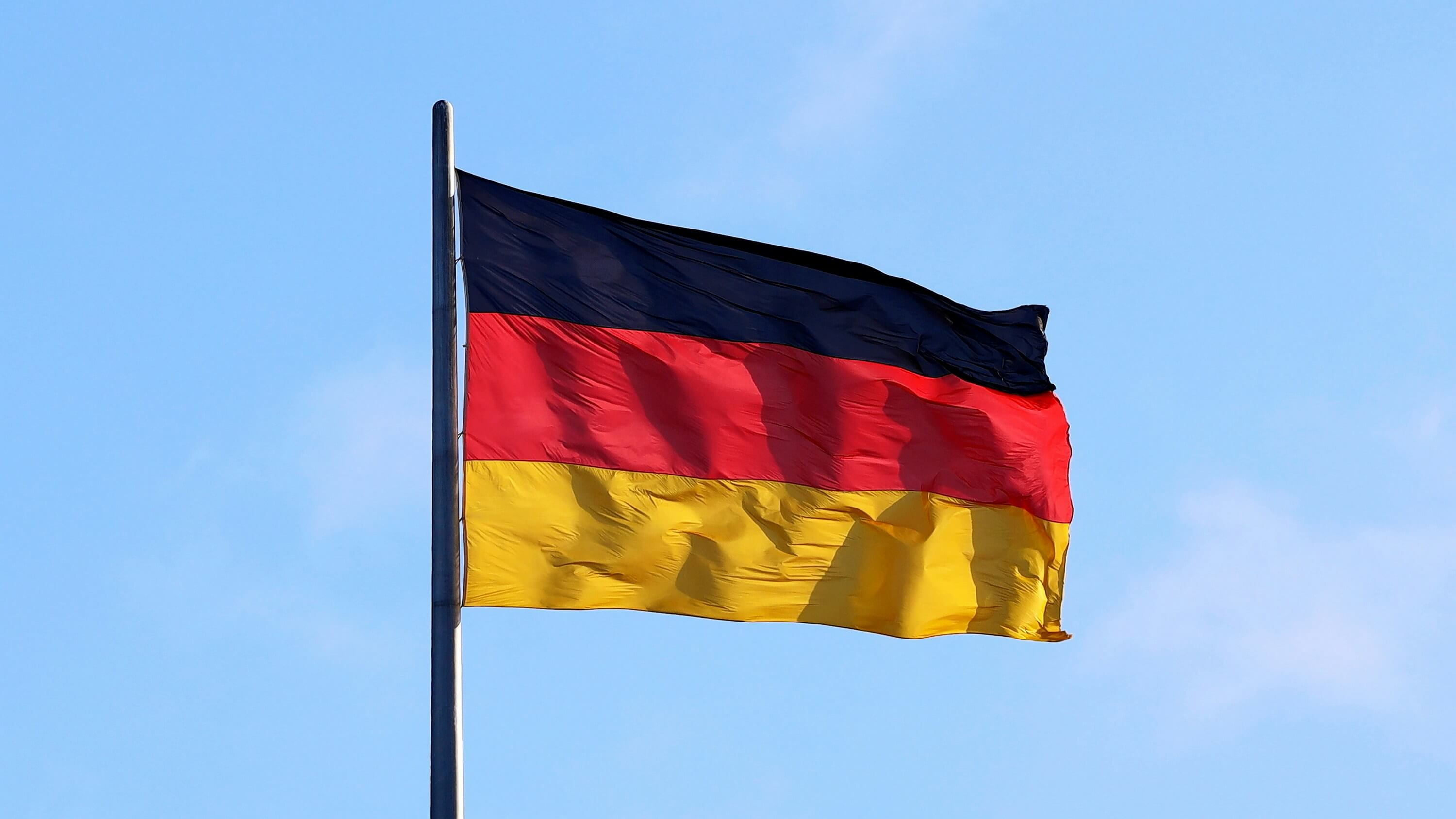 The German flag with a blue sky background. loading=lazy